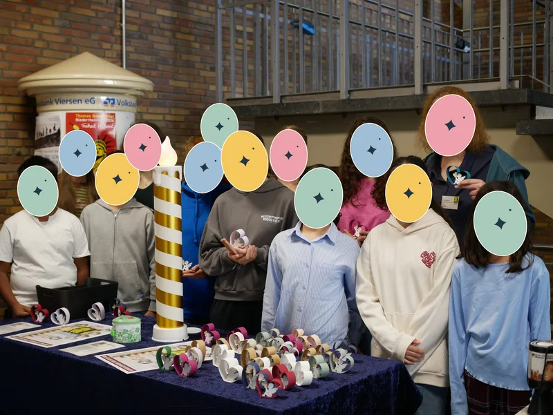Eine Gruppe präsentiert selbst gebastelte Papierherzen und kleine Figuren am Stand.