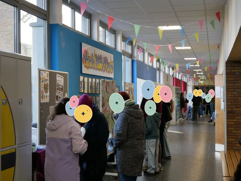 Besucherinnen und Besucher im mit bunten Wimpelgirlanden geschmückten Schulgang.