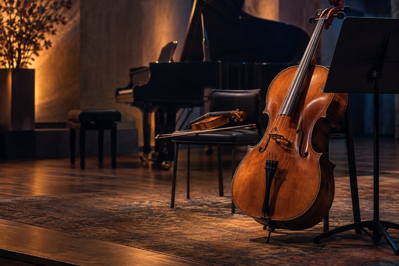 Cello, Geige und Klavier auf einer warm beleuchteten Bühne – KI-Symbolbild