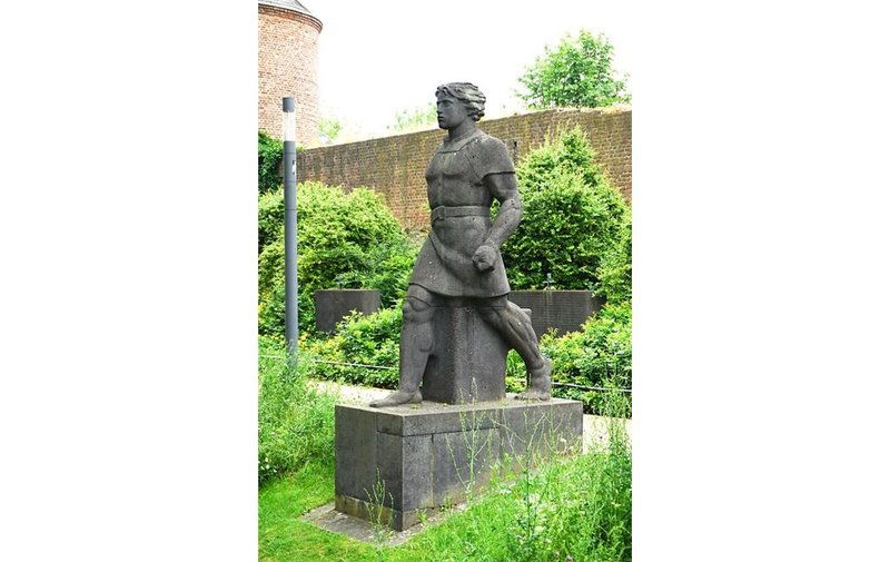 Siegfried-Figur mit Schwert vor der Dülkener Stadtmauer, dahinter Gedenksteine und ein Teil des Gefangenenturms