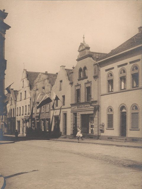 Historische Fotografie von 1911: Dülkener Giebelhäuser mit Läden und einer Person auf der Straße.
