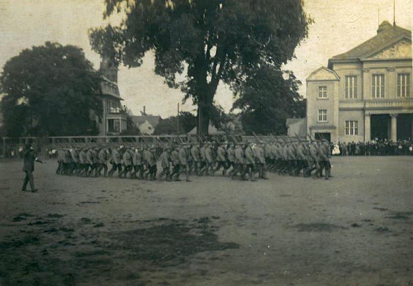 Historische Fotografie einer marschierenden Gruppe auf dem Platz vor der Viersener Festhalle; vermutlich 1915.